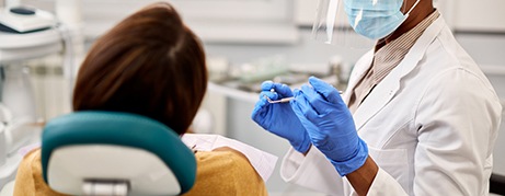 Dentist with PPE conducting exam