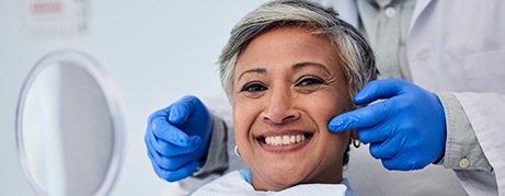 Woman smiling while holding handheld mirror