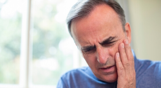 Man holding his cheek in pain before emergency dentistry in Commack