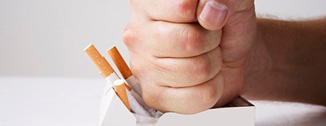 A hand crushing a carton of cigarettes