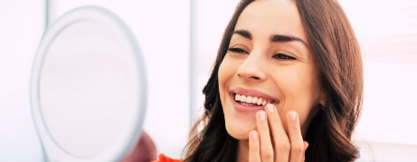 Young woman admiring her smile in a mirror