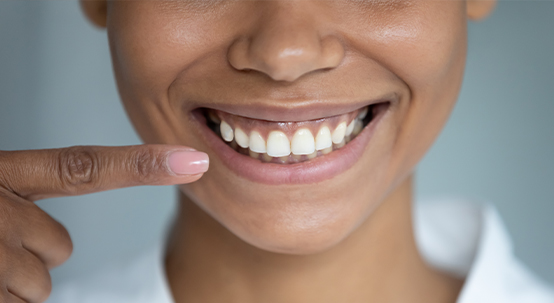 Person pointing to their smile after gum disease treatment in Commack