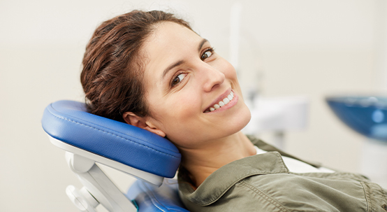 Woman smiling in dental chair during preventive dentistry visit