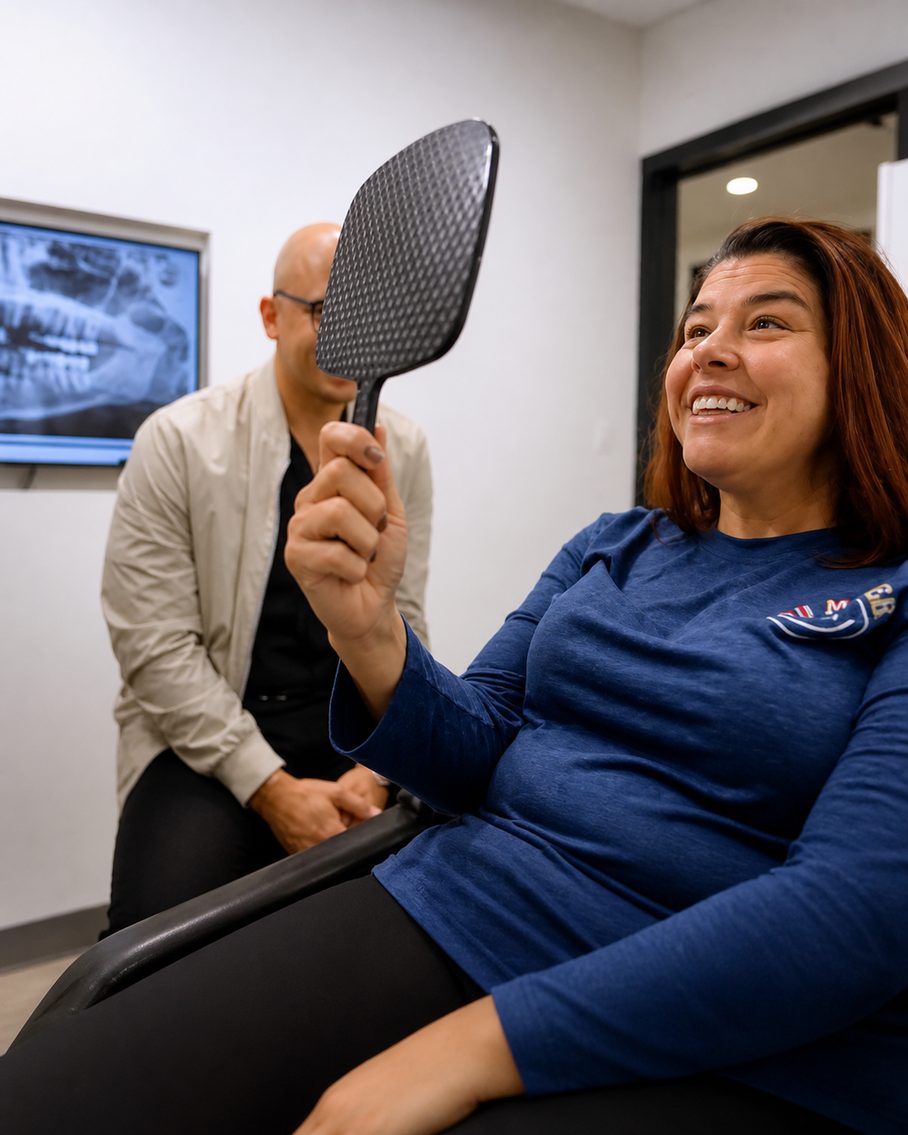 Salina looking at her new smile in a hand mirror with Dr. Silfa