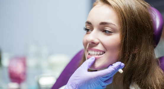 Woman smiling in dental chair after restorative dentistry in Commack