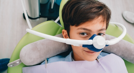 Young boy in dental chair wearing nose mask for nitrous oxide sedation dentistry
