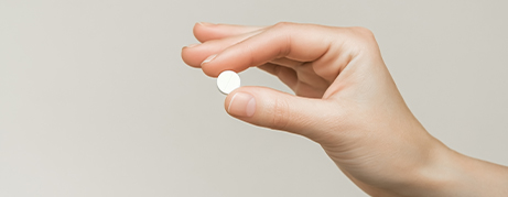 Hand holding a white pill