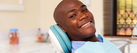 Man smiling in dental chair after receiving dental services in Commack