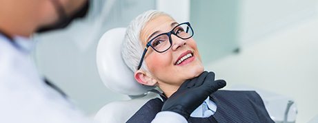Woman with black glasses smiling at dentist
