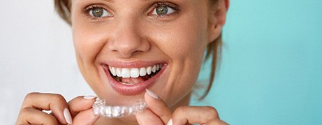 Smiling patient holding teeth whitening tray