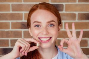 Woman smiling while holding a tooth