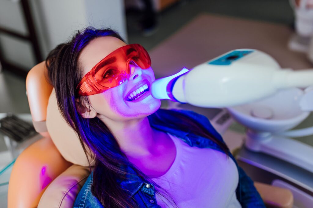 Woman undergoing teeth whitening at dental office